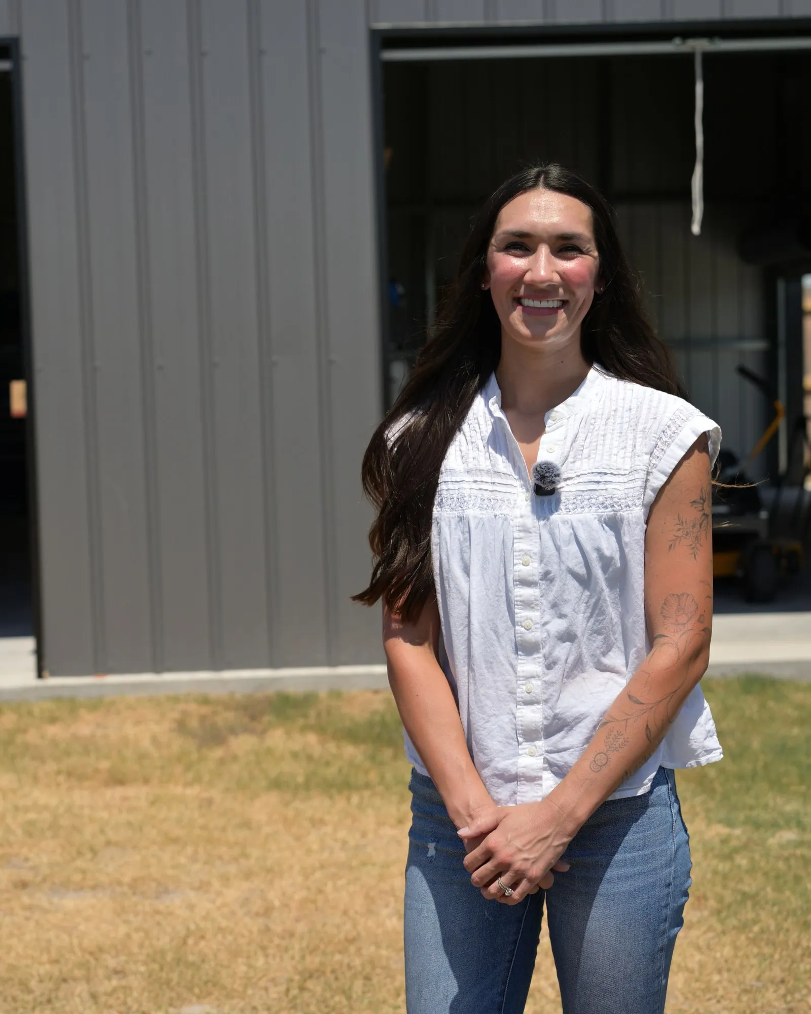 Brittany, the customer, standing in front of her custom gray metal shop in Greenville, Texas