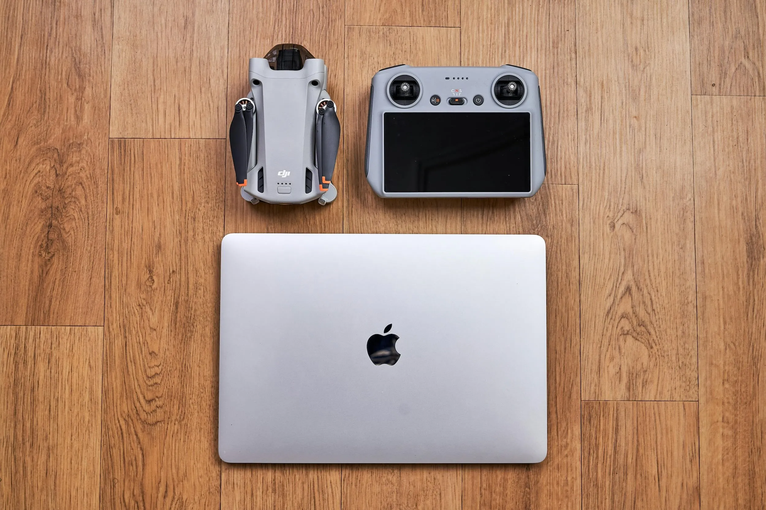 Folded drone, smart remote controller, and laptop arranged on a wooden floor
