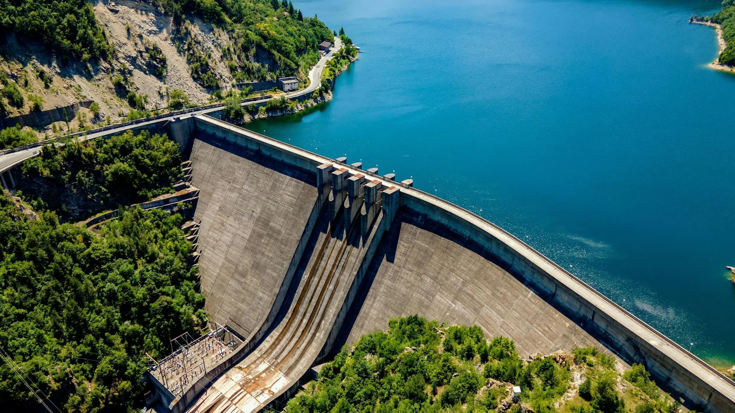 Aerial drone view of a concrete dam and reservoir in regulated airspace
