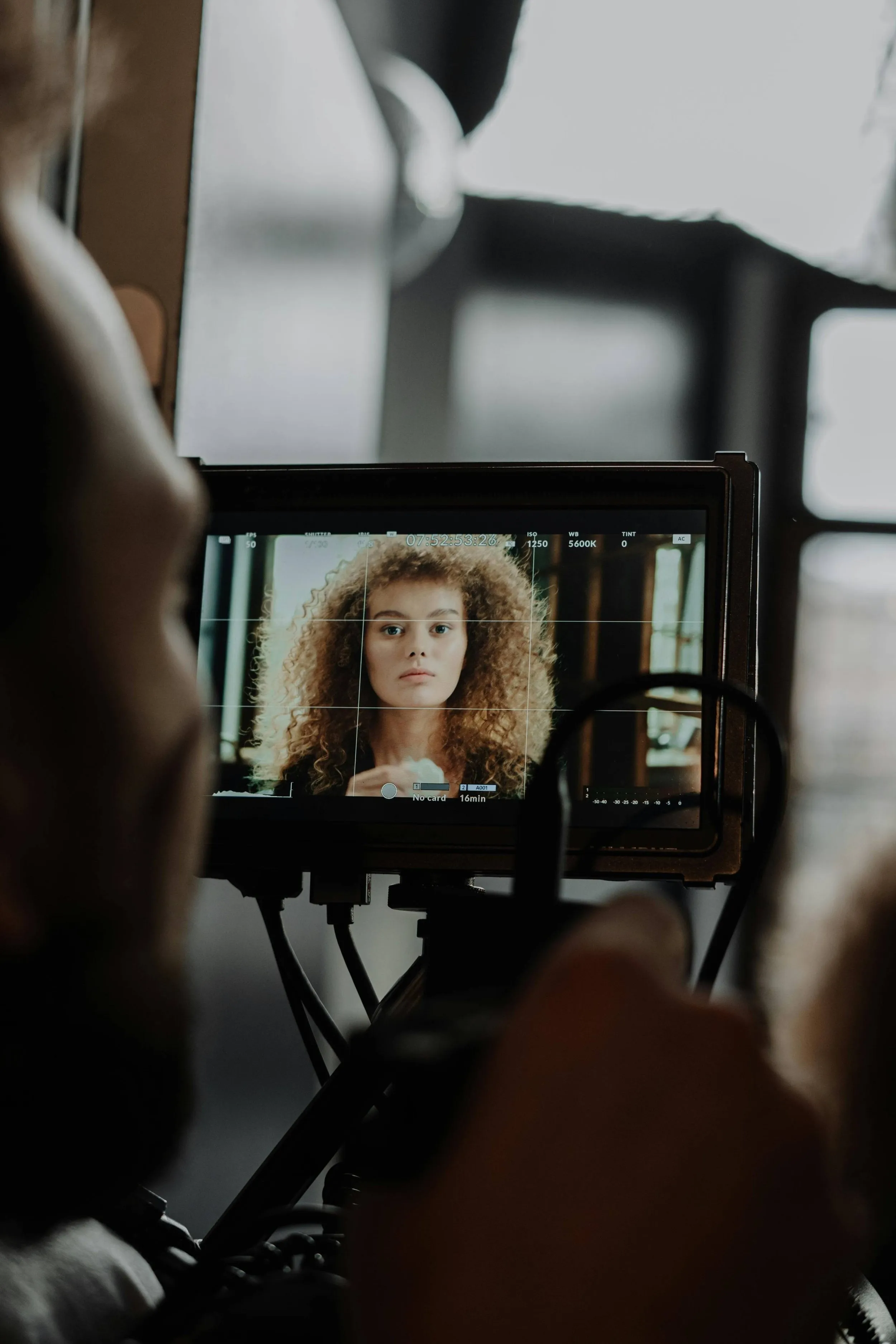 Camera operator checking portrait framing on a production monitor during a studio photo session