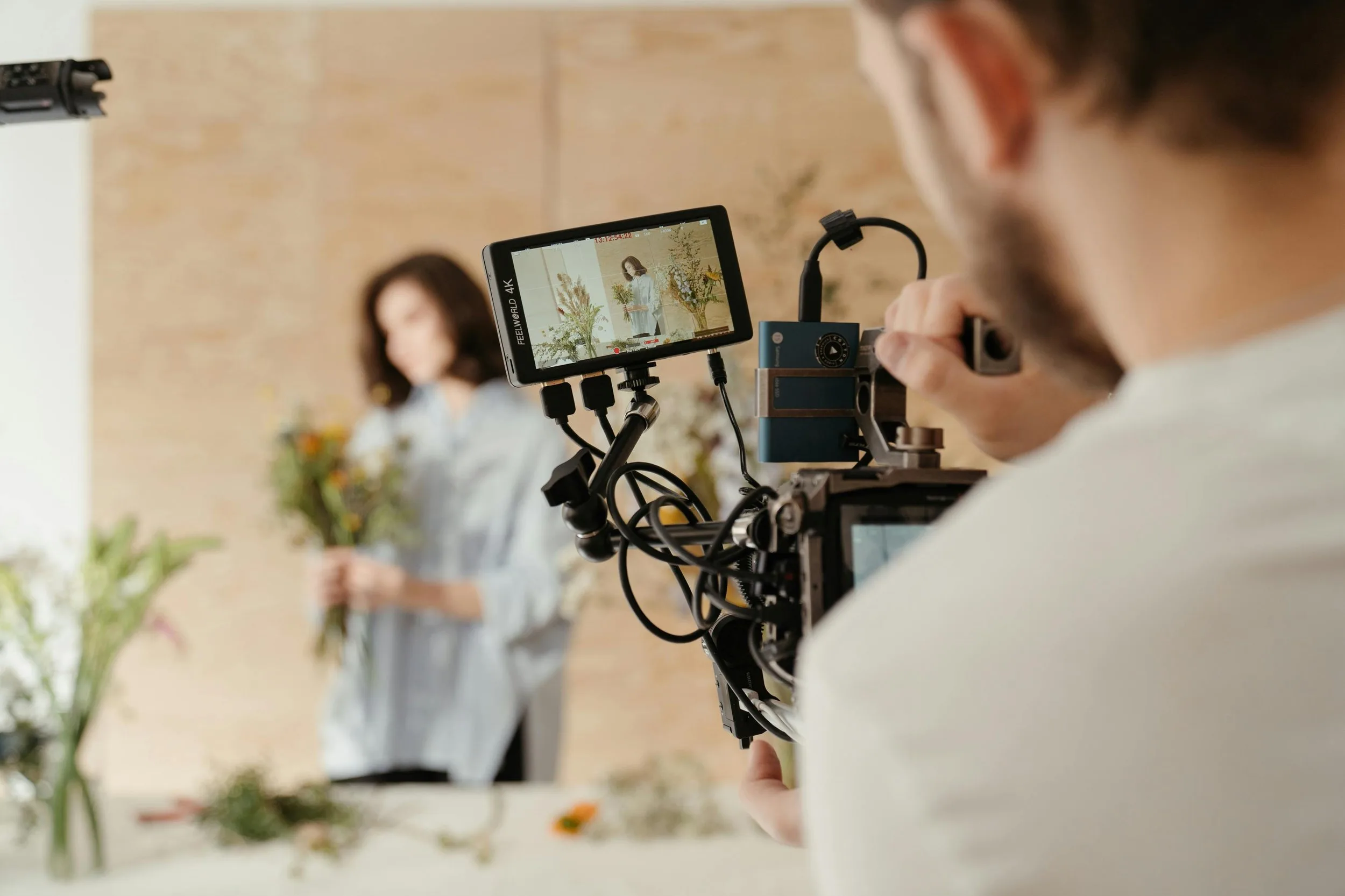 Camera operator filming a small business owner with a cinema camera and 4K field monitor during a social media content shoot